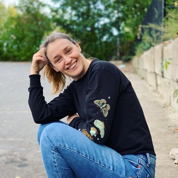 Femme souriante en tenue décontractée en extérieur.