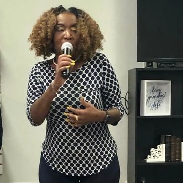 Woman speaking into a microphone during a presentation or speech.