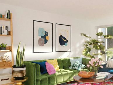 Bright living room with green sofa, colorful cushions, abstract wall art, and plants.