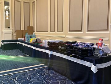 Table with various items and boxes in a conference room.