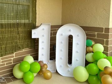 Large marquee number 10 surrounded by green and gold balloons.