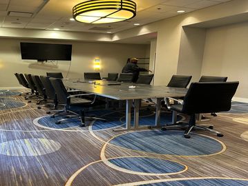 Modern conference room with large table and black swivel chairs.