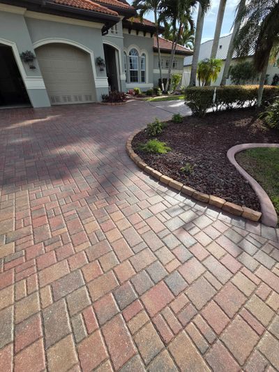 A clean brick driveway leading to a garage of a suburban home.