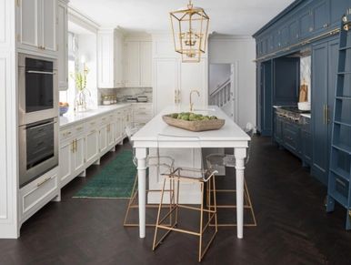 Modern kitchen with white and navy blue cabinetry and transparent chairs.