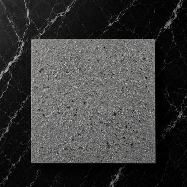Square terrazzo tile on black marble surface.