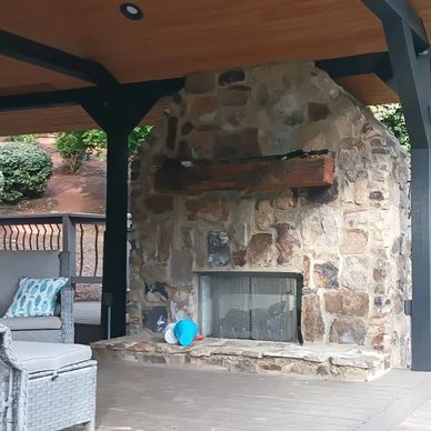 Outdoor stone fireplace under a wooden roof.