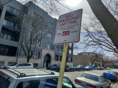 Street with a 'No Parking Anytime' sign and several parked cars.