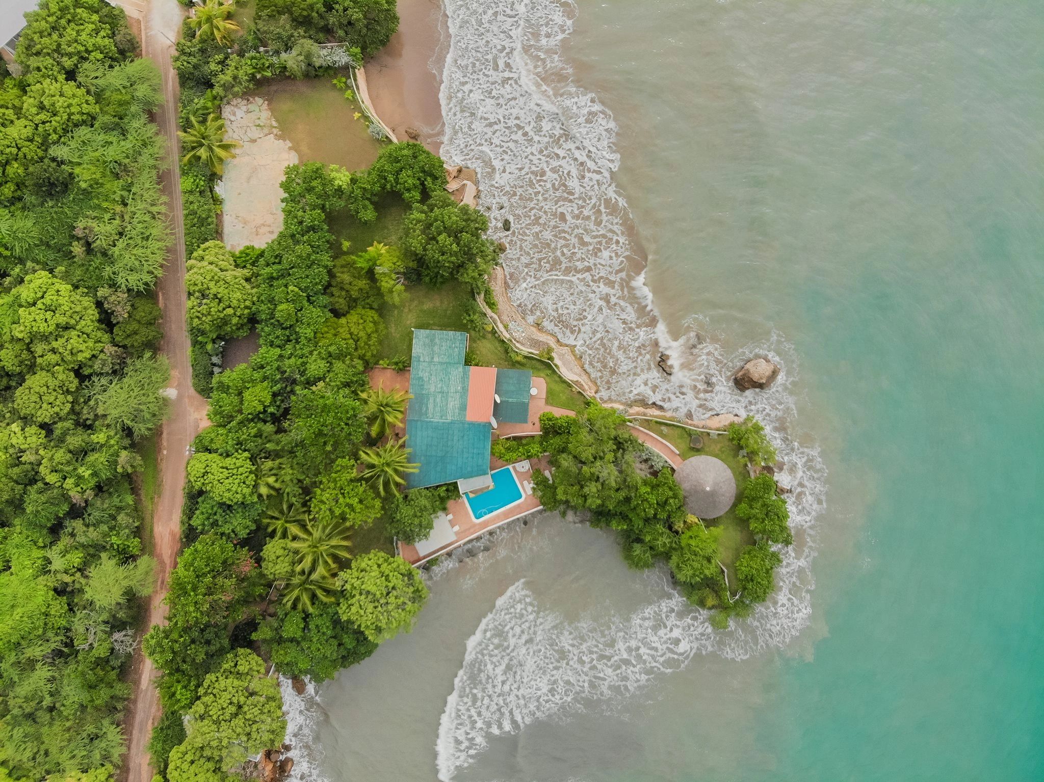 Aerial view of a green house near the ocean shore.