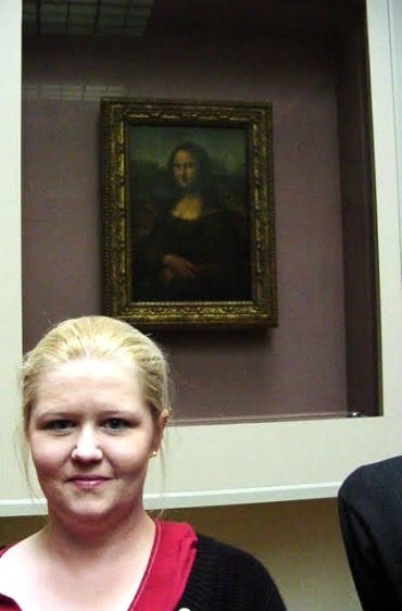 Woman posing in front of the Mona Lisa painting.
