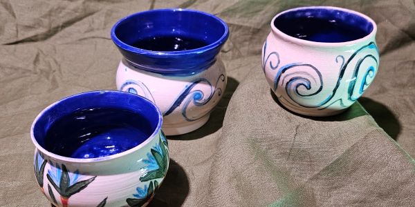Three artistic ceramic bowls with blue interiors and designs.