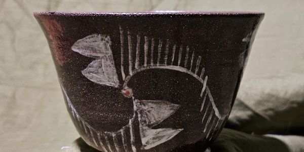 Close-up of a dark pottery bowl with white fishbone design.