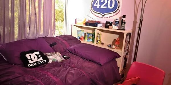 Cozy bedroom with purple bedding and 420-themed decor.