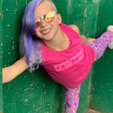 A girl wearing a pink tank top and purple leggings with colorful patterns