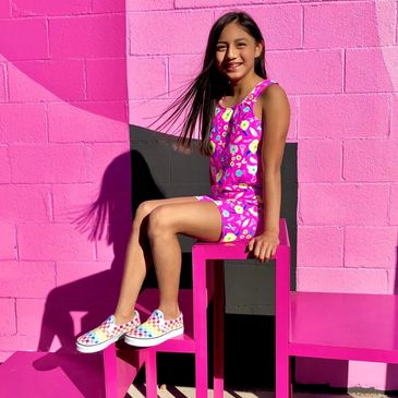 A girl wearing a pink dress with dragonfly and flower patterns
