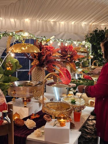 Elegant buffet setup with golden dishes, fall-themed decor, and warm lighting.