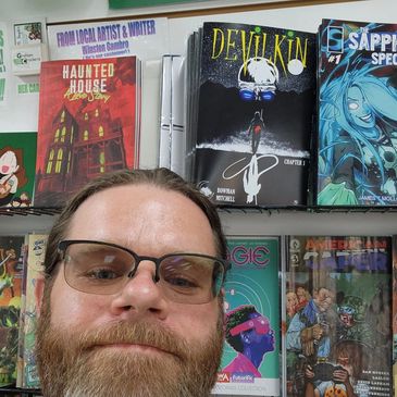 Man taking a selfie in front of comic books.