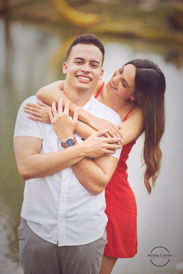 A happy couple embracing outdoors with the woman smiling at the man.