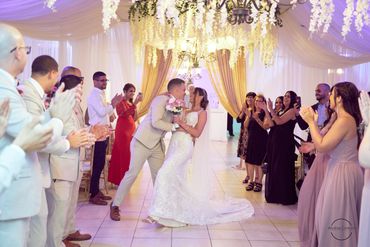 Newlyweds share a joyful kiss as guests applaud during the wedding ceremony.