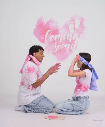 Couple with paint on clothes revealing a pregnancy announcement with "Coming soon" text.