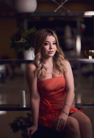Young woman with blonde hair in a red dress posing indoors.