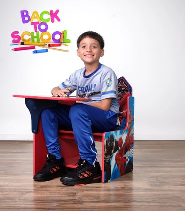 Smiling boy sitting at a Spider-Man themed school desk, ready for back to school.