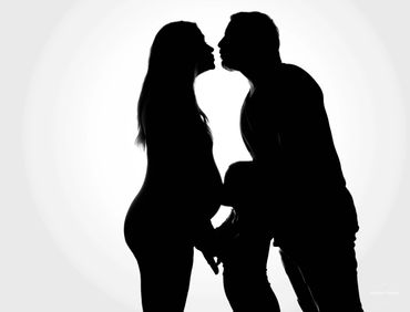 Silhouette of a pregnant woman and a man sharing a tender moment.