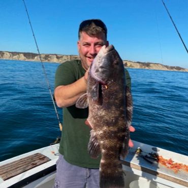 Man proudly holding a large fish on a boat.