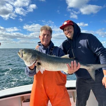 Two men holding a large fish on a boat.
