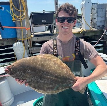 Young man holding a large flatfish on a boat.