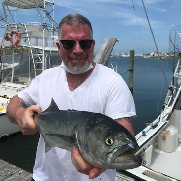 Man holding a large fish on a boat.