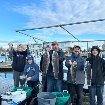 Group holding large fish on a dock.