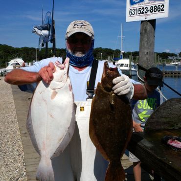 Man holding two large fish at a dock.