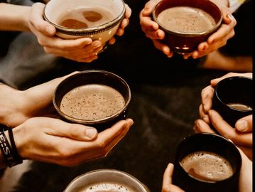 Hands holding bowls of hot cacao.