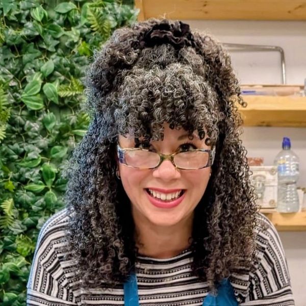 Smiling woman with curly hair and glasses.