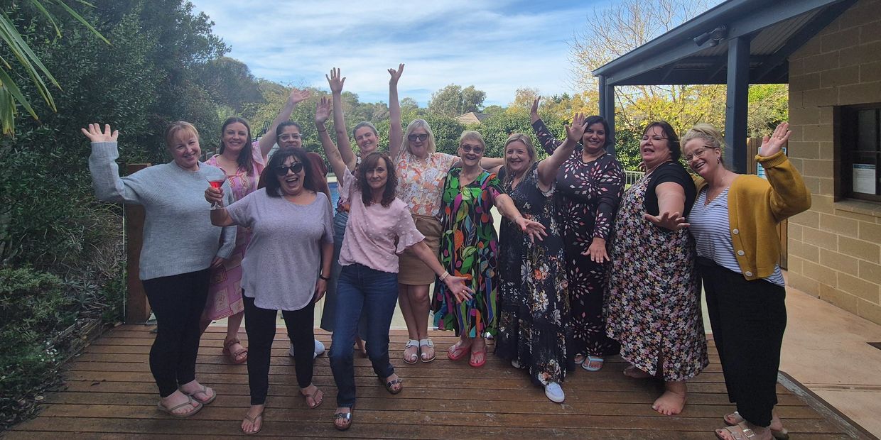 A group of women standing in a line smiling and posing