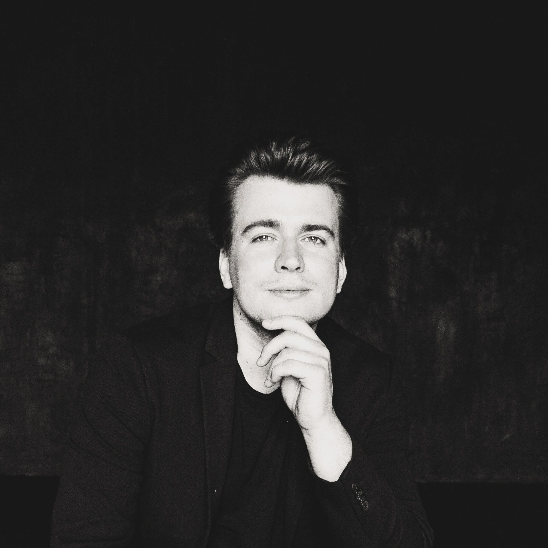 Black and white portrait of a man with hand on chin.