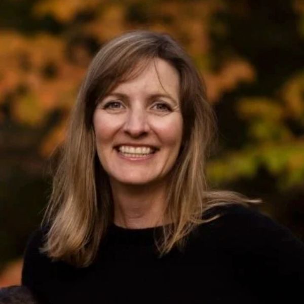 Smiling woman with light brown hair outdoors.