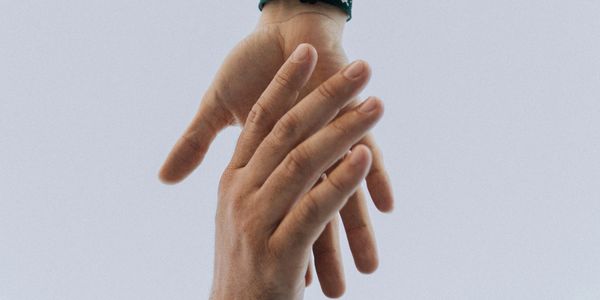 Two hands reaching out to each other against a plain background.