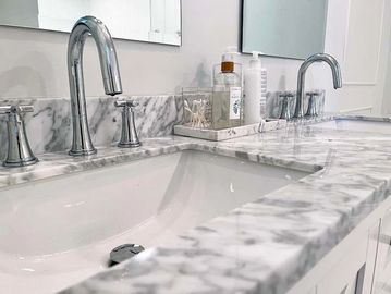 New faucets on a double vanity with marble countertop