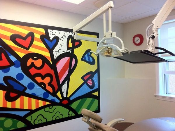 Pediatric dental operatory room with dental equipment and colorful mural of hearts.