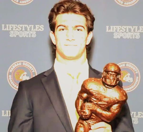 Young man holding a football trophy at an awards event.