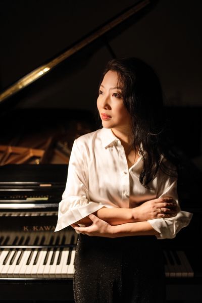 Dr. Ying Zhang Standing by the Piano