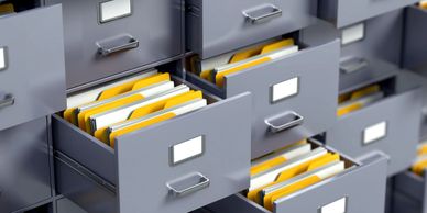 Opened and closed filing cabinets, with yellow and white organised files inside them