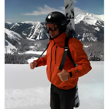 Skier in orange jacket with goggles holding gear in a snowy mountain landscape.