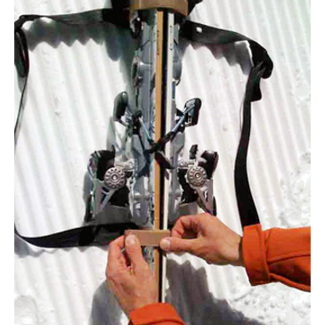 Hands attaching gear straps to skis for carrying/packing in snow.