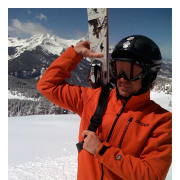 Skier adjusts black helmet, holding skis over shoulder on snowy slope.