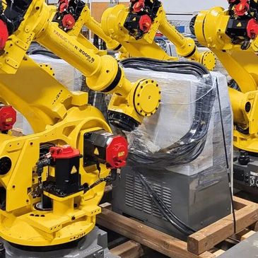 Yellow industrial robotic arms working on machinery in a factory setting.