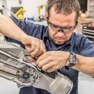 Man wearing safety glasses repairing a mechanical device.