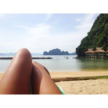 Person relaxing on a beach with a scenic island view.