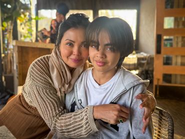 A woman warmly hugging a young boy indoors.